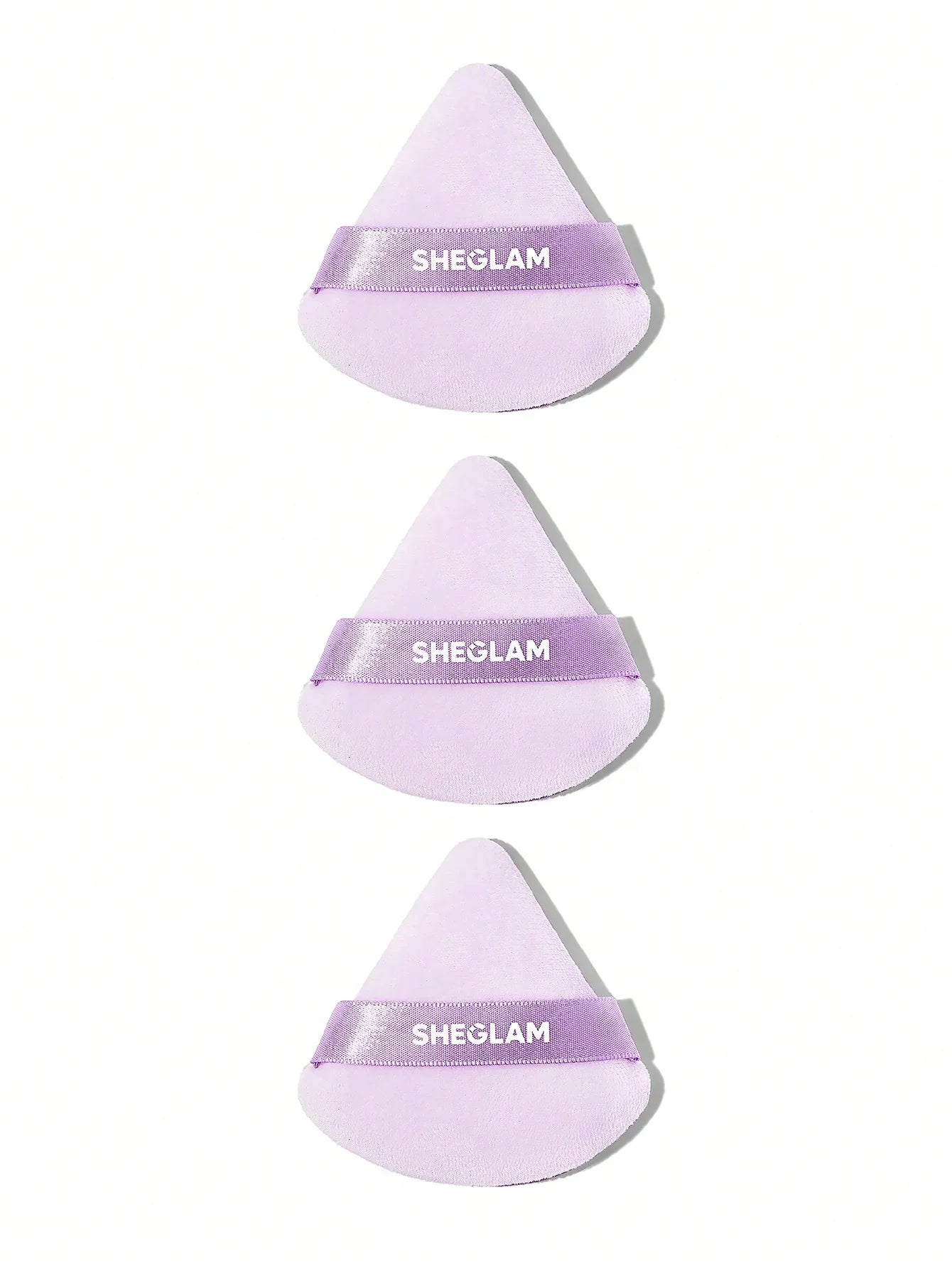 Three lavender SHEGLAM makeup sponges with ribbon bands, ideal for flawless cosmetic application.