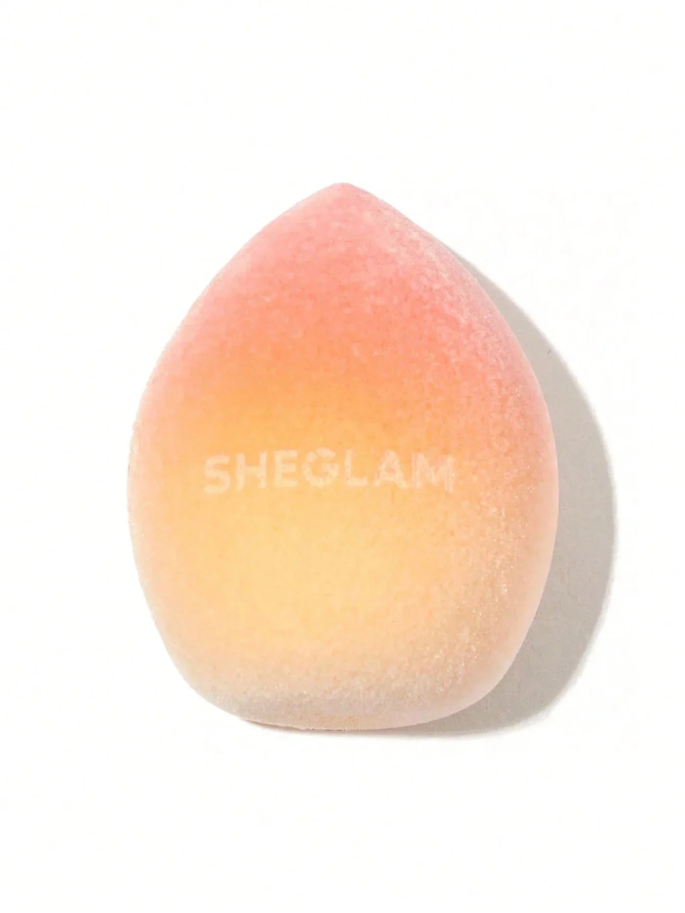Sheglam makeup sponge with peach-to-orange gradient, ideal for flawless cosmetic application